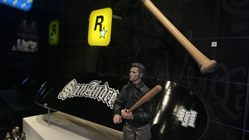 Rockstar Games lamp, skateboard advertising GTA: San Andreas, baseball bat, and Claude figure from GTA 3.